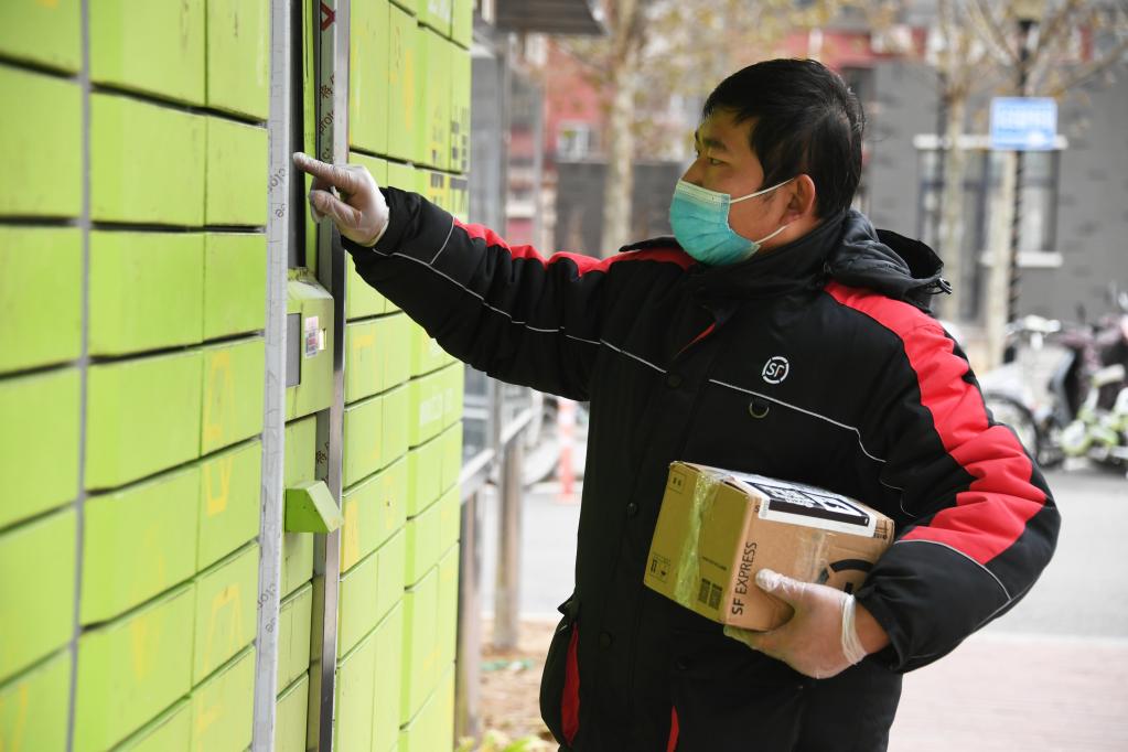 2021年11月20日在位于北京市海淀区学院路街道的惠博嘉园小区，工作人员准备将快递物品放入快递柜。新华社记者 任超 摄