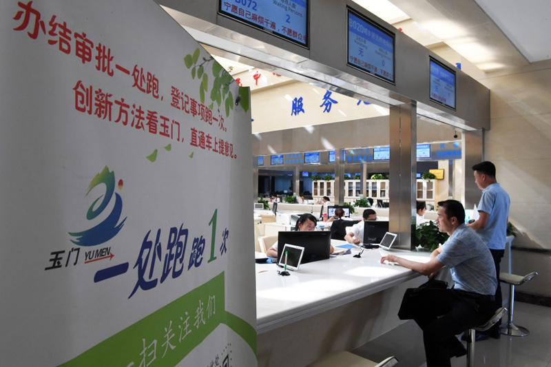 在甘肃省玉门市民中心服务大厅，市民在窗口办理业务（2018年8月17日摄）。2017年以来，甘肃省玉门市不断深化“放管服”改革，推行“一窗办一网办简化办马上办”，基本实现群众、企业办事只往市民中心服务大厅一处跑，跑一次就能办结所有审批和服务事项。新华社记者范培珅摄